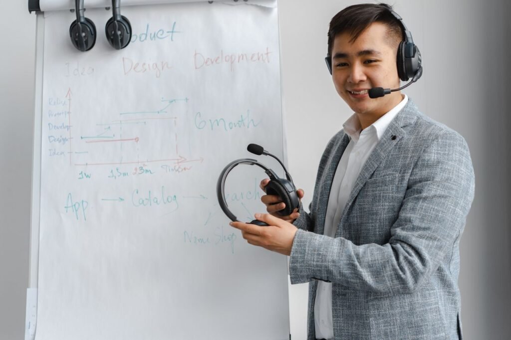 Asian man explaining a concept in a training session with a headset and flip chart.