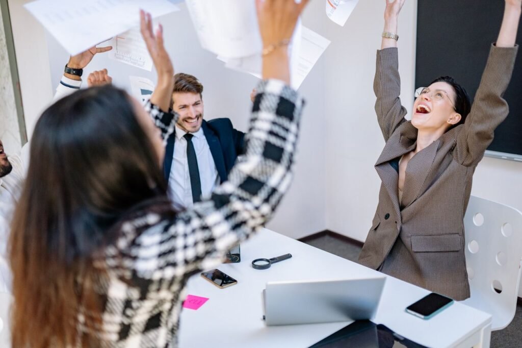 Diverse business team celebrating success with joy in a modern office setting.